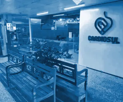 Entrada da Cardiosul no hall de lojas, com o logo na parede e bancos de madeira na frente