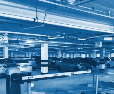 Estacionamento coberto do Open Mall, com a cancela de entrada e carros estacionados